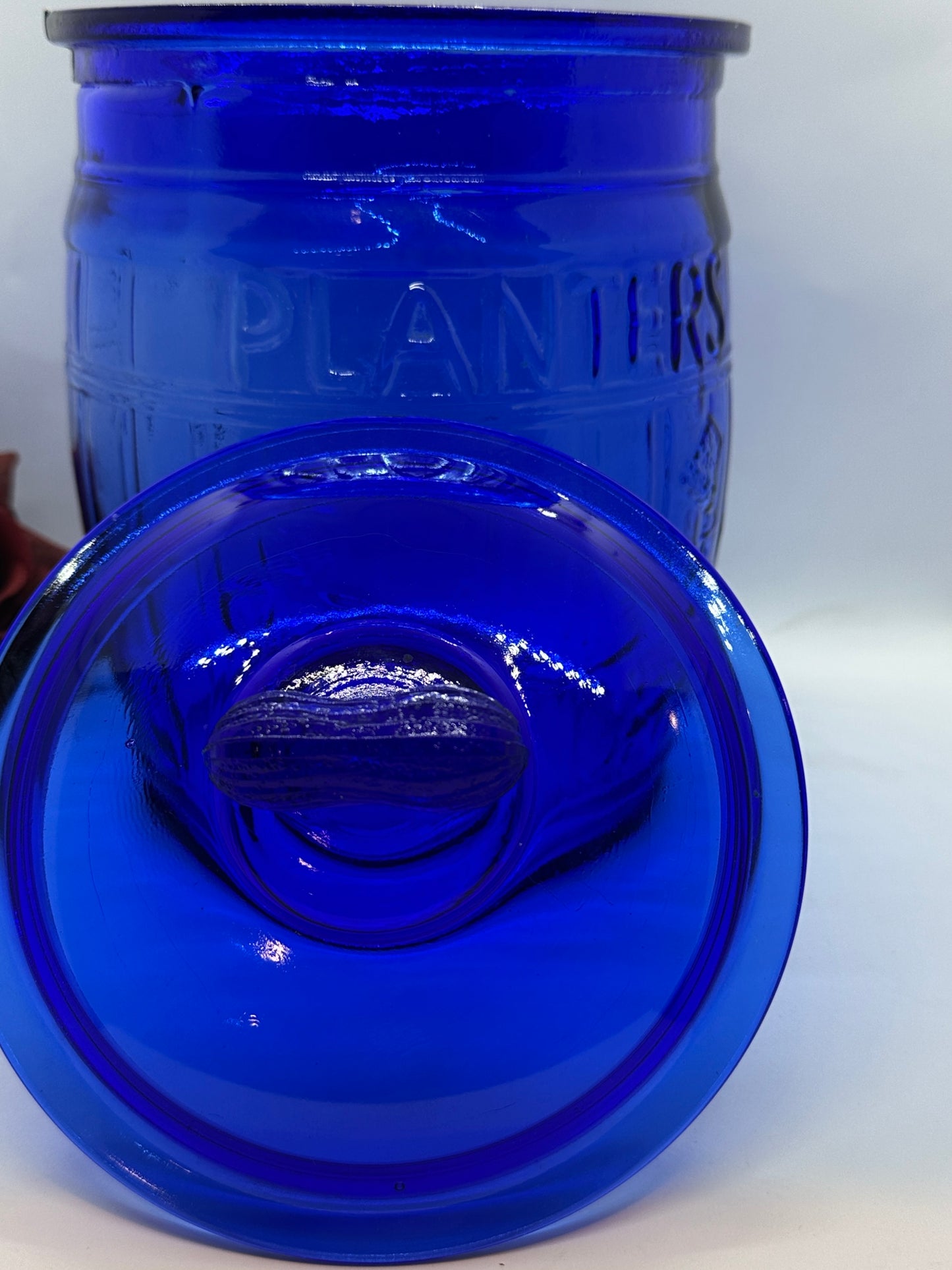 Close-up of a blue glass jar lid on a plain background.