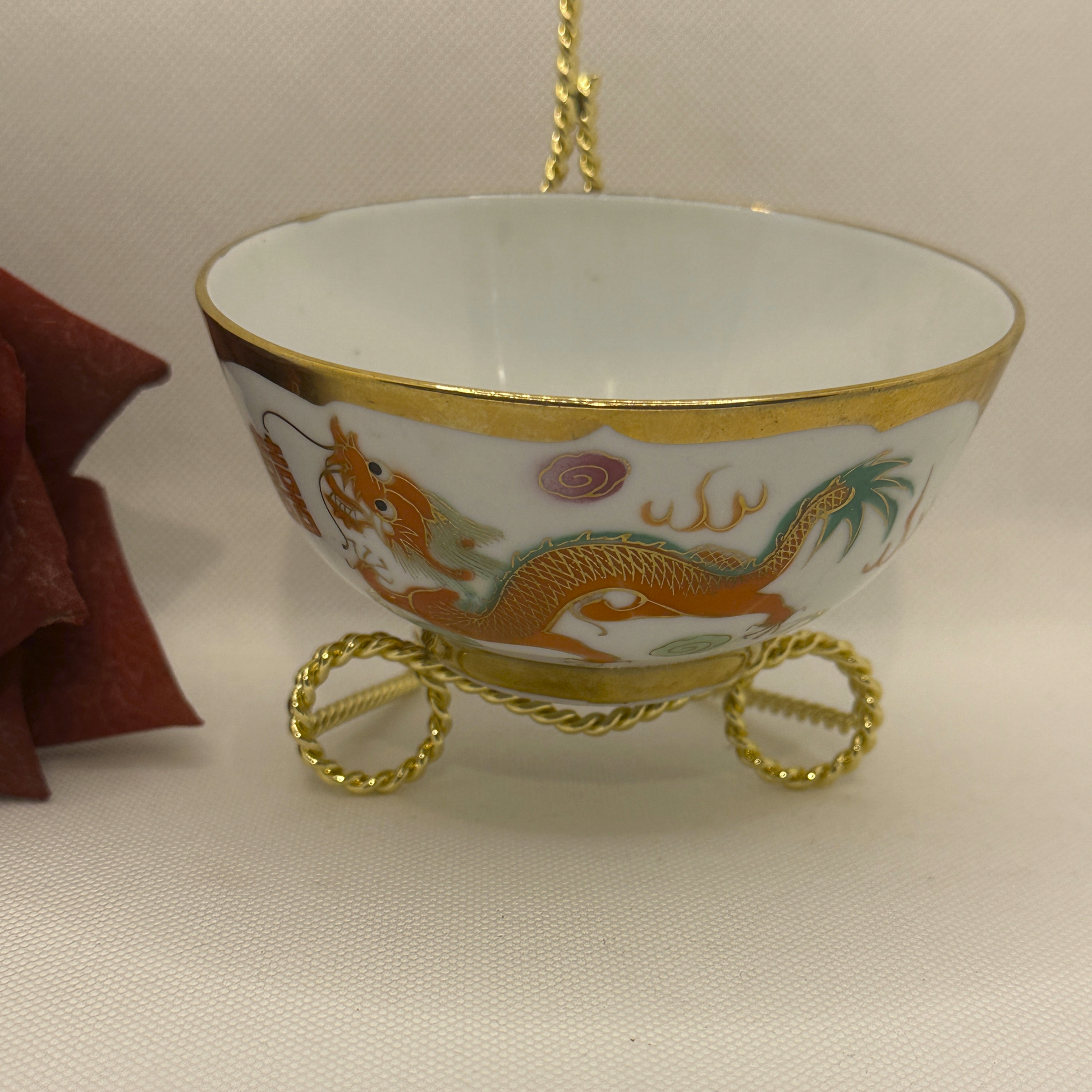Decorative ceramic bowl with dragon design on a stand against a neutral background