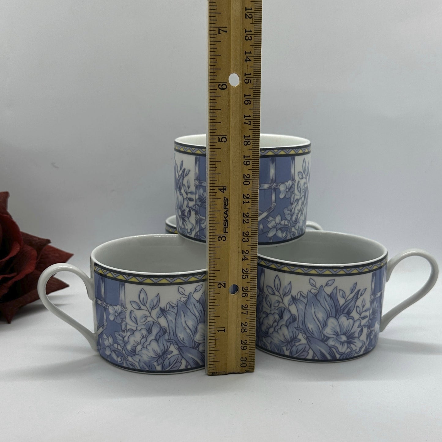 Four blue and white patterned mugs with a ruler for scale.