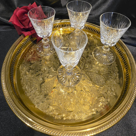 Set of crystal glasses on a gold tray with a red rose against a black background