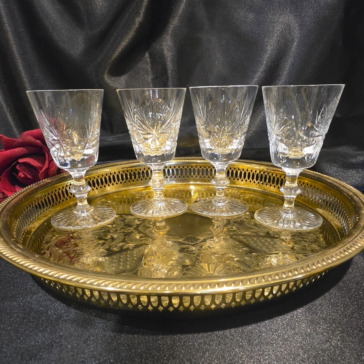Four crystal glasses on a gold tray with a dark background