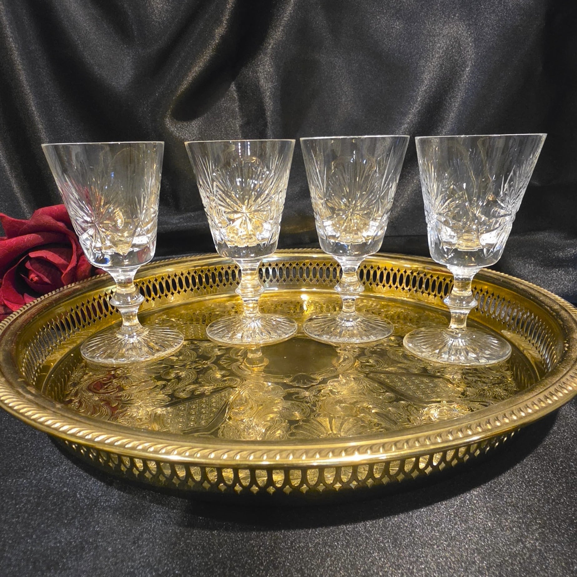 Four crystal glasses on a gold tray with a dark background