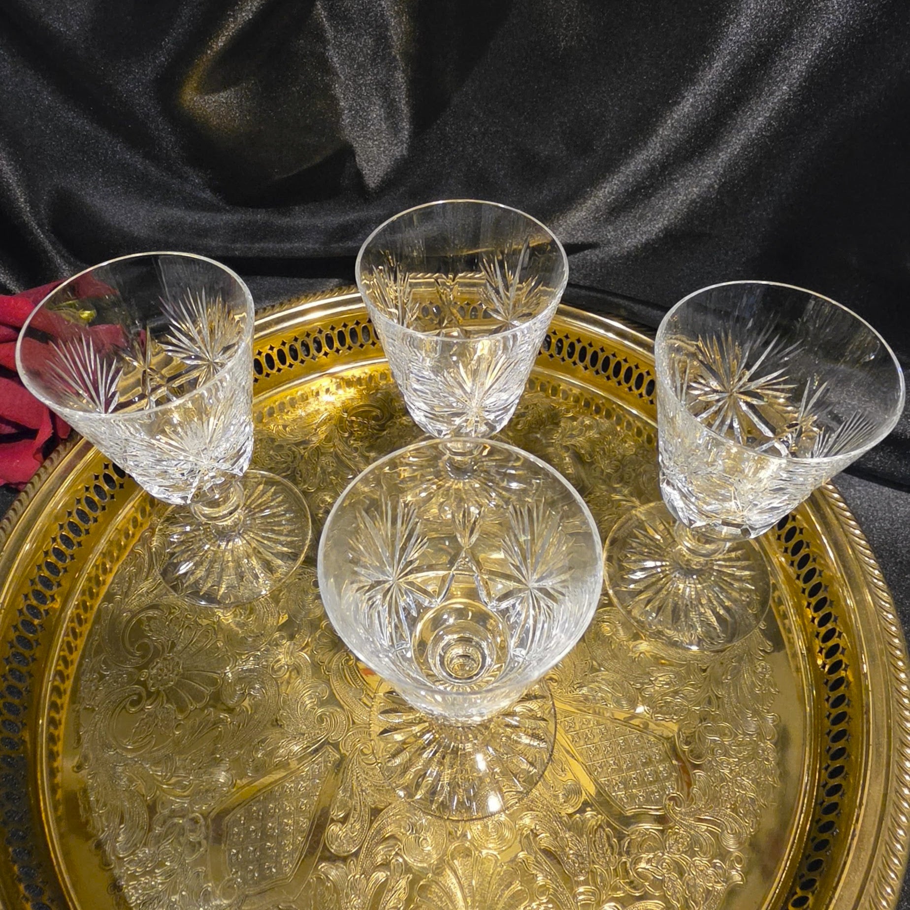 Set of four crystal glasses on a decorative gold tray with a dark background